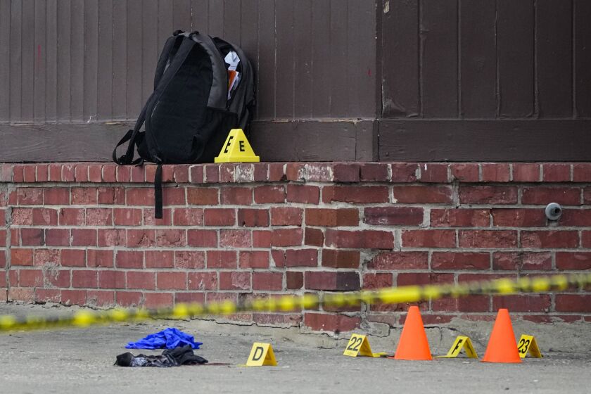 A backpack is seen near evidence markers at the site of a shooting near Edmondson Westside High School, Jan. 4, 2023, in Baltimore. In response to rising youth violence, Baltimore leaders are ramping up efforts to de-escalate conflicts between young people and protect students going to and from school. (AP Photo/Julio Cortez)