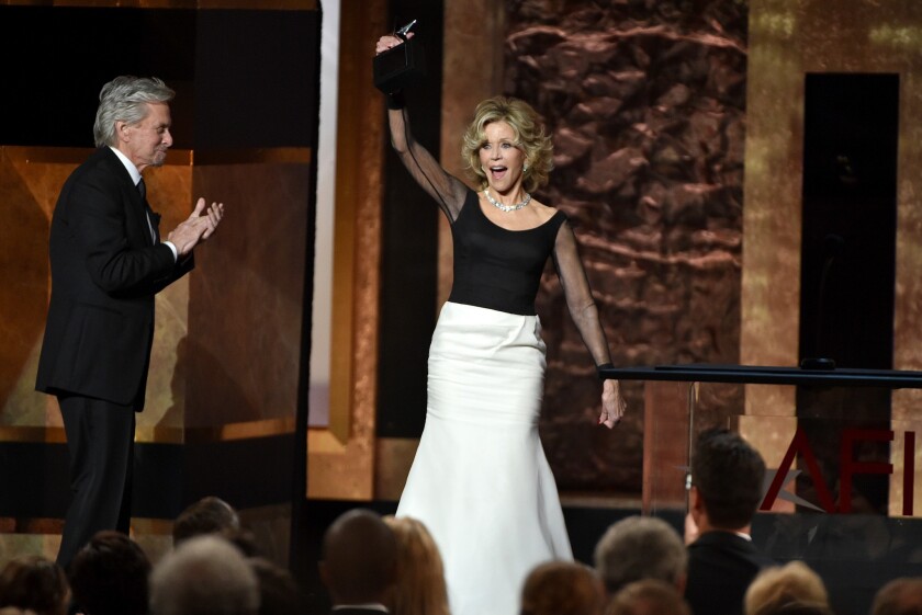 Jane Fonda accepts her lifetime achievement award from AFI as presenter Michael Douglas applauds.