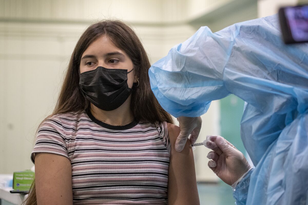 A nurse gives a Pfizer-BioNTech vaccine shot to Gizelle Carrillo, 14, at Eagle Rock High School.