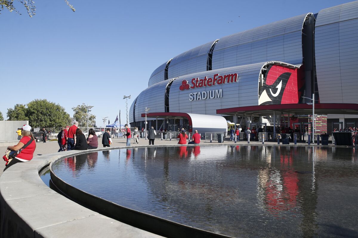 Fans sit and walk around a reflecting pool outside State Farm Stadium in Glendale, Ariz.