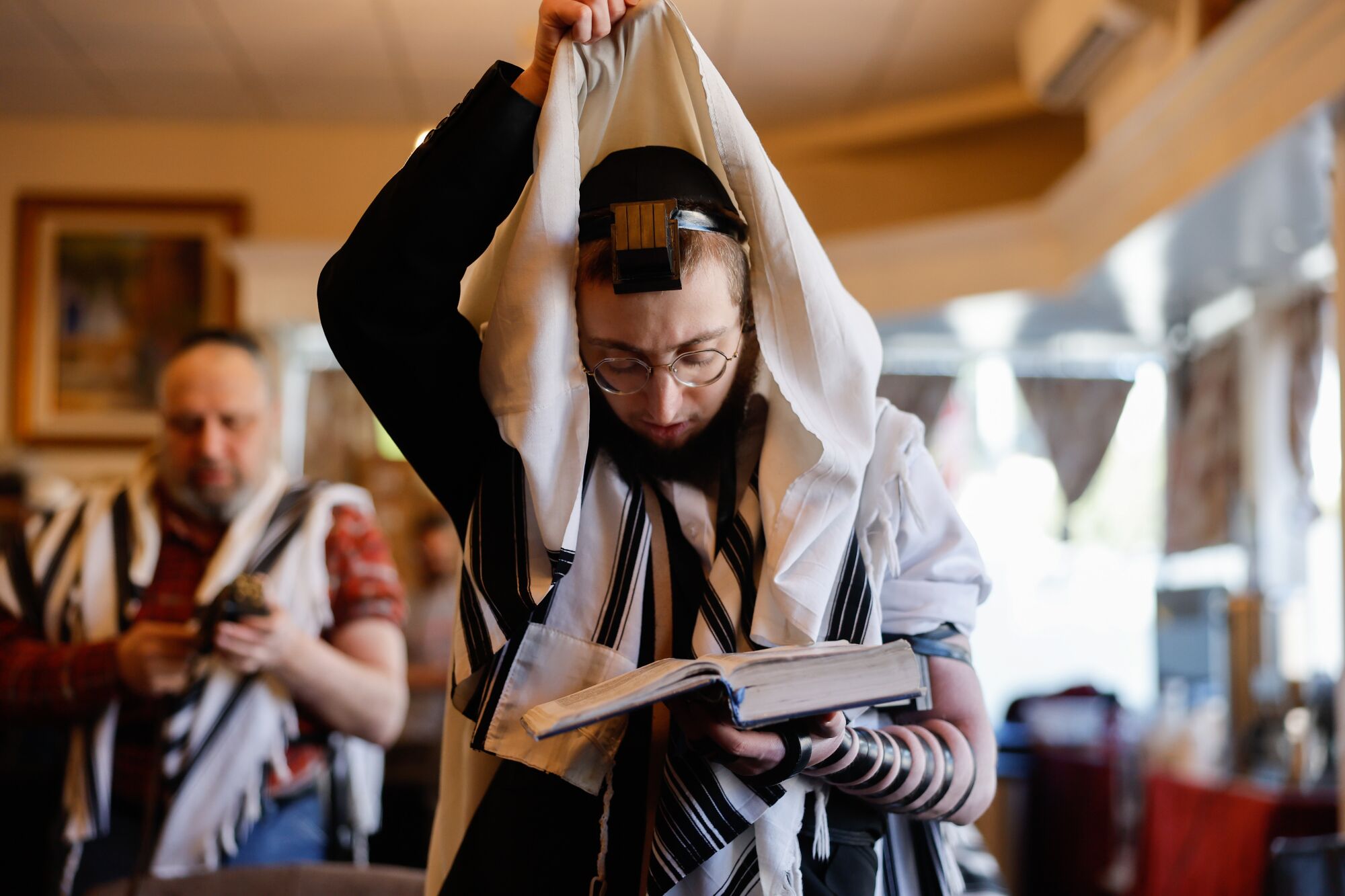 A rabbi dons a prayer shawl in temple.