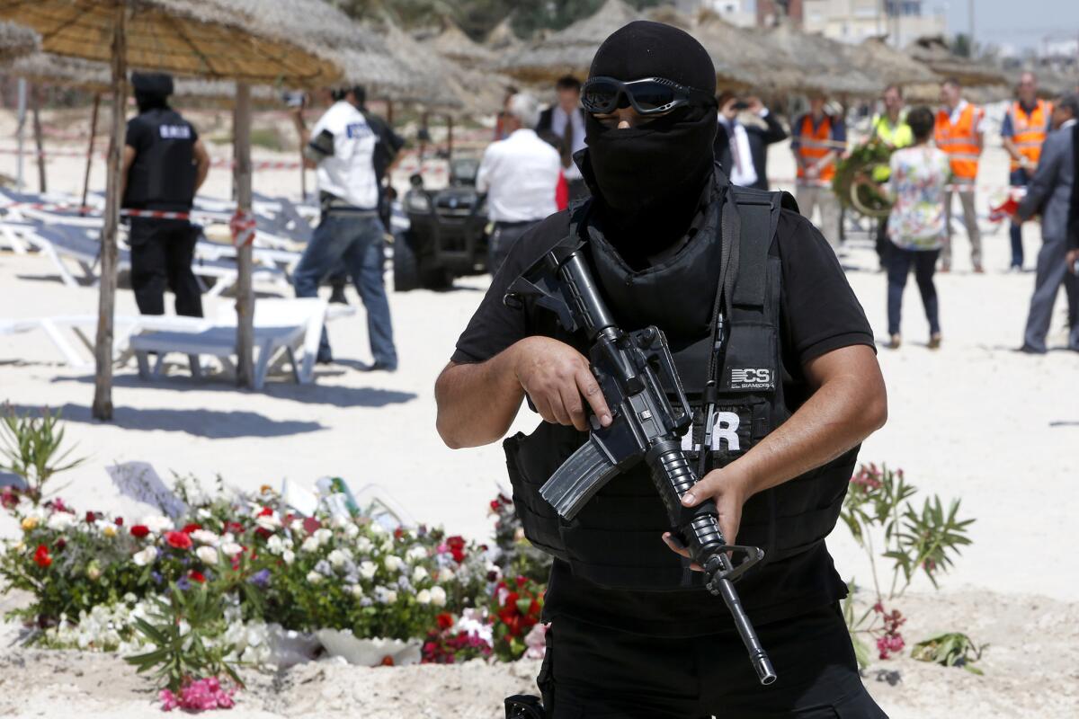 Un policía tunecino encapuchado hace guardia durante la visita de responsables de seguridad de Gran Bretaña, Francia, Alemania y Bélgica al lugar del atentado extremista del pasado viernes, en el hotel Imperial Marhaba del centro vacacional mediterráneo de Susa, en Túnez, el 29 de junio de 2015. (Foto AP/Abdeljalil Bounhar)