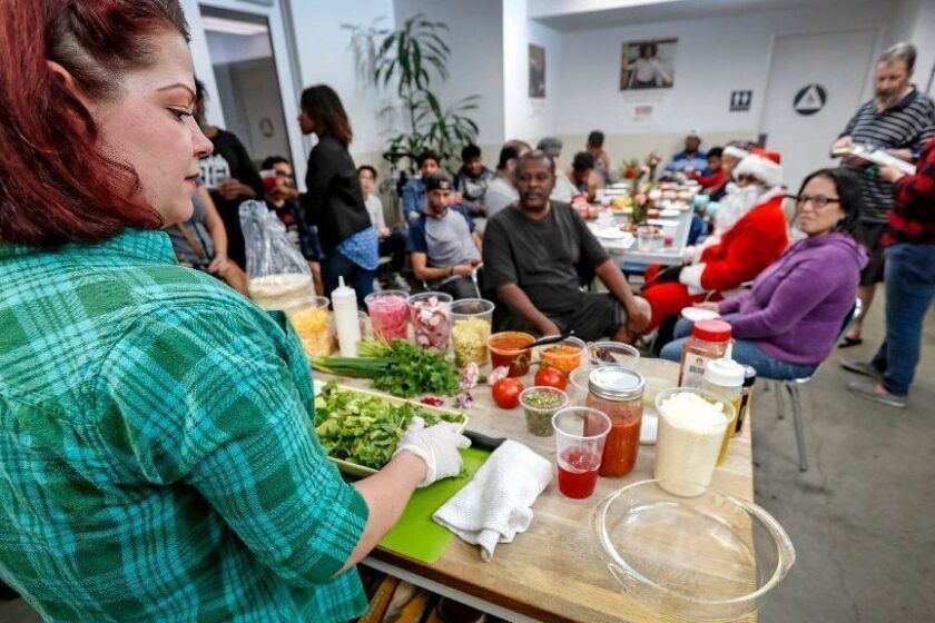 LOS ANGELES, CALIF. - DEC. 19, 2018. Chefs Sara Kenas demonstrates how to make a salad during an evening gathering for residents of the Cobb Apartments in downtown Los Angeles on Wednesday, Dec. 19, 2018. The Skid Row Housing Trust has a program that features chesfs who visit the housing project to teach residents where and how to buy and prepare ingredients for heatlhy and tasty meals. Kenas is a partner in a pop-up restaurant called Anarchy Seafood. (Luis Sinco/Los Angeles Times)