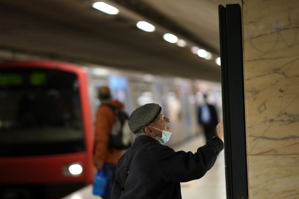 A man wearing a face mask on his chin checks a map at a subway station, Thursday, Jan. 6, 2022. Portugal's government has announced new incentives for people to get COVID-19 booster shots. People who had a booster jab two weeks previously will from next Monday no longer need to show a negative coronavirus test result to attend events and enter places where it otherwise would be required. (AP Photo/Armando Franca)
