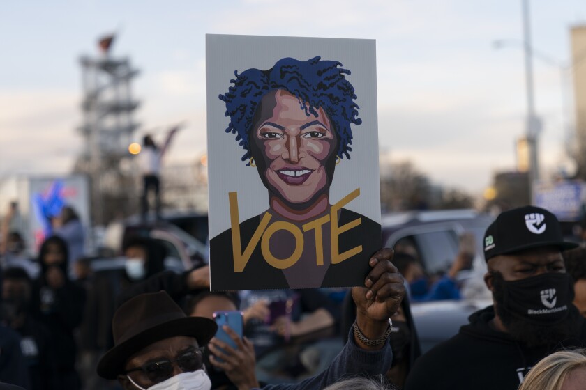 People in the crowd hold up an image of Stacey Abrams as President-elect Joe Biden speaks in Atlanta, Monday, Jan. 4, 2021, to campaign for Georgia Democratic candidates for U.S. Senate, Rev. Raphael Warnock and Jon Ossoff. (AP Photo/Carolyn Kaster)