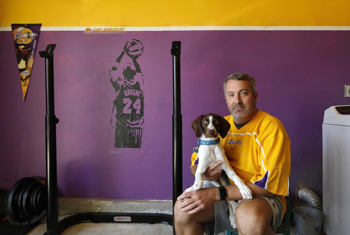 Matthew Crooks holds the family dog "Kobe" in his Huntington Beach garage. 