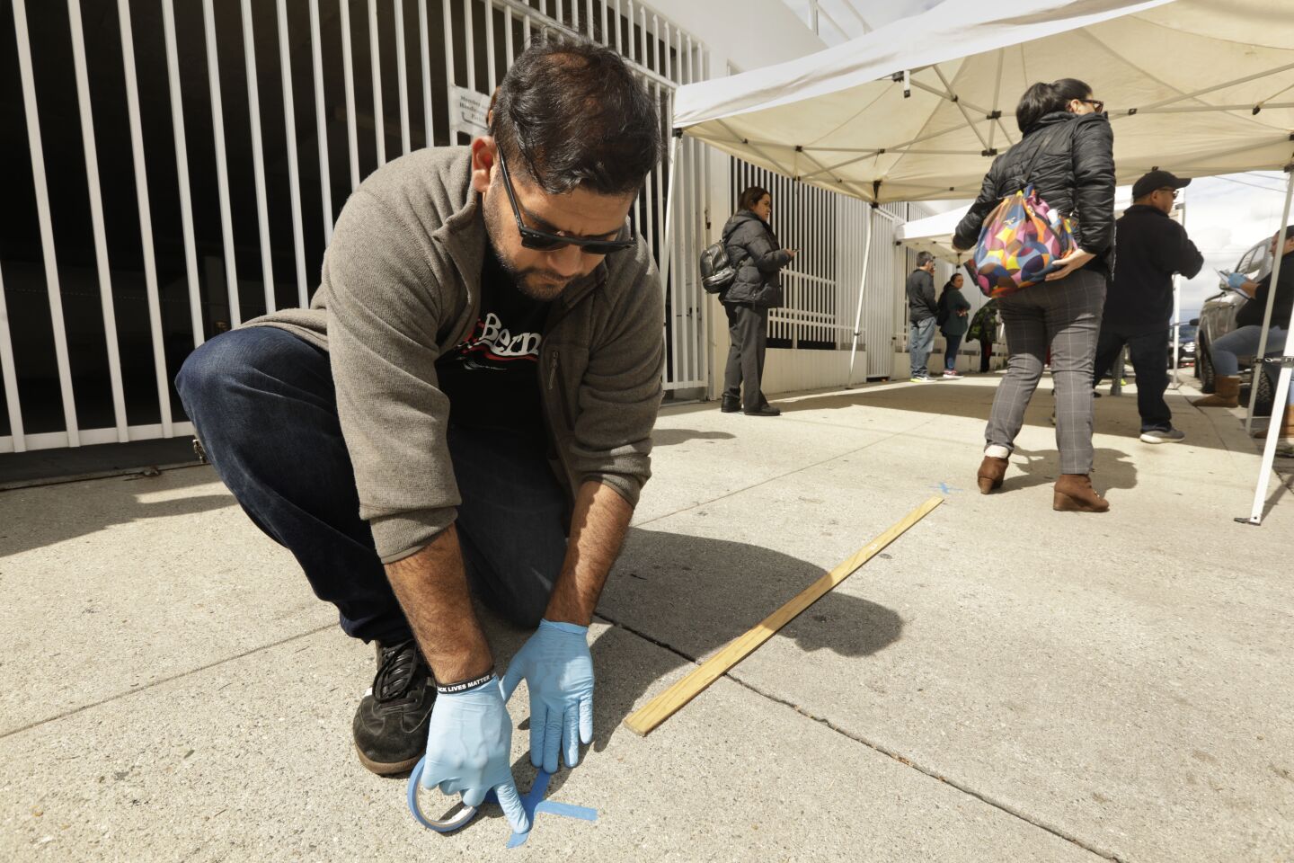 Hugo Soto-Martinez marks spots every six feet for proper social distancing in the line at a Unite Here Local 11 food bank.