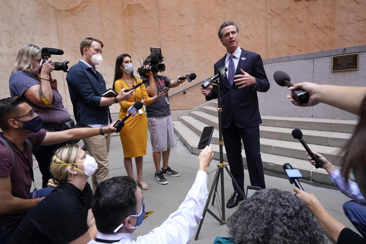 Gavin Newsom surrounded by reporters with microphones
