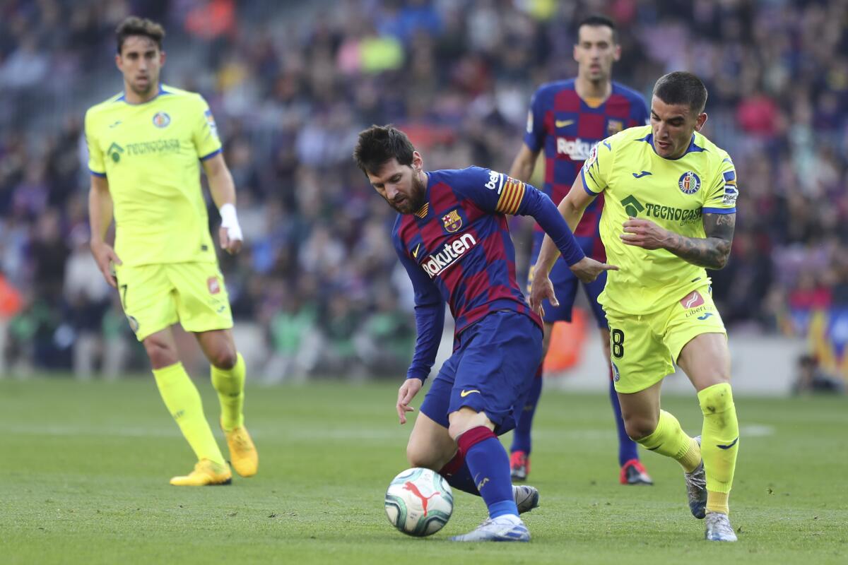 El delantero argentino Lionel Messi (izquierda) del Barcelona domina el balón ante el asedio de Mauro Arambarri del Getafe en el partido de la Liga española en Barcelona, el sábado 15 de febrero de 2020. (AP Foto/G. Garín)