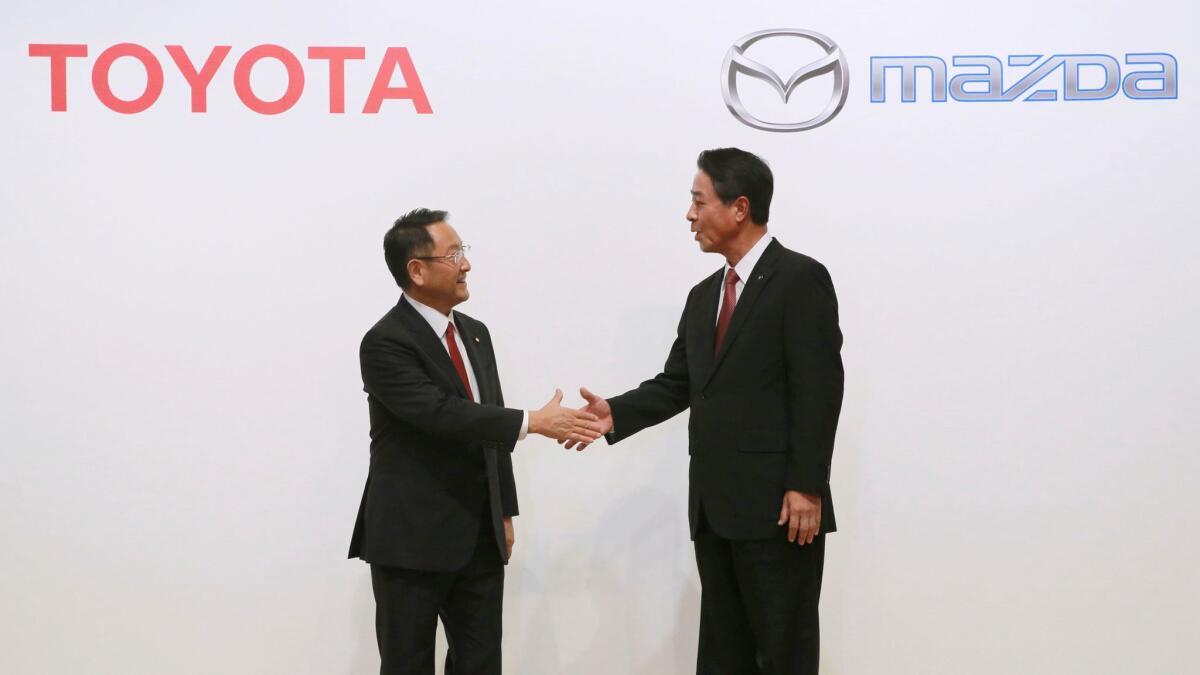 Toyota President Akio Toyoda, left, and Mazda President Masamichi Kogai shake hands in August 2017.