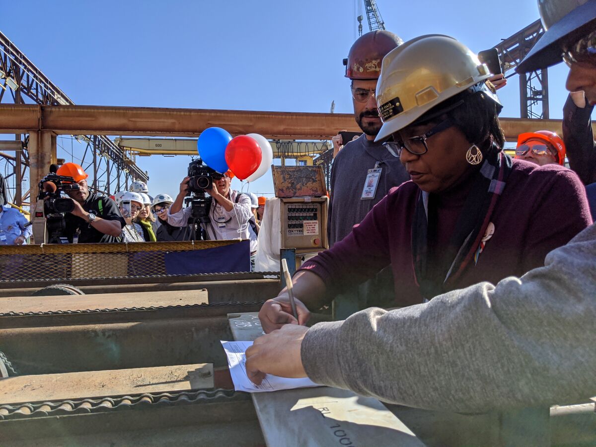 Kathy Baker, center, signs off on the ceremonial first cut of steel for the future Harvey Milk on Friday at General Dynamics NASSCO in San Diego.