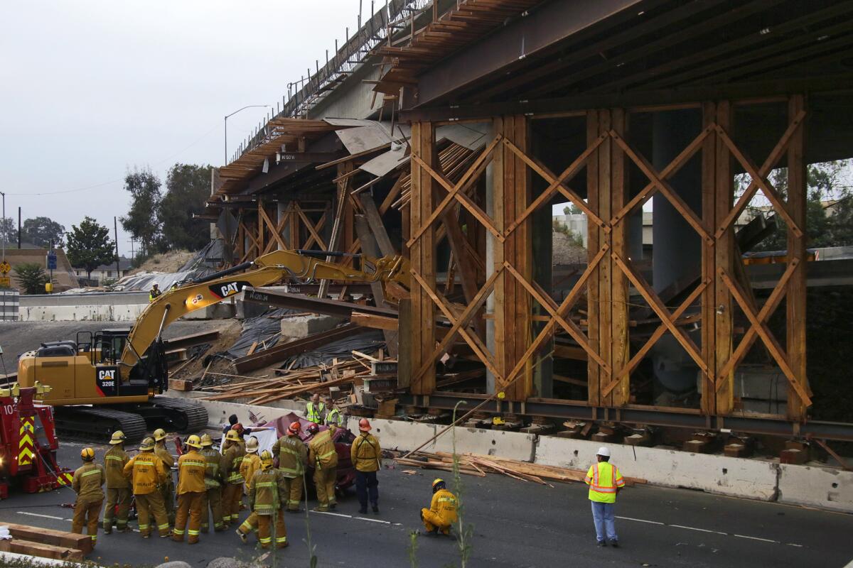 Los Angeles County firefighters work to retrieve the body of the driver of a car that crashed into temporary supports for a widened 710 Freeway overpass at the 5 Freeway interchange in Commerce.