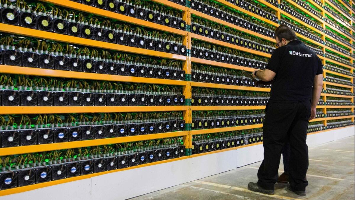 Two technicians inspect bitcoin mining at Bitfarms in Saint Hyacinthe, Canada, in March 2018.