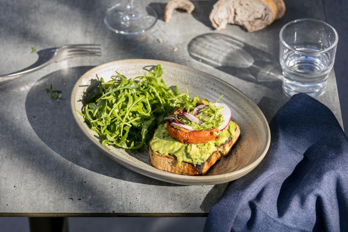 An avocado toast at Pikoh served on house quinoa bread with oven-dried tomato, radish, yuzu aioli and micro greens