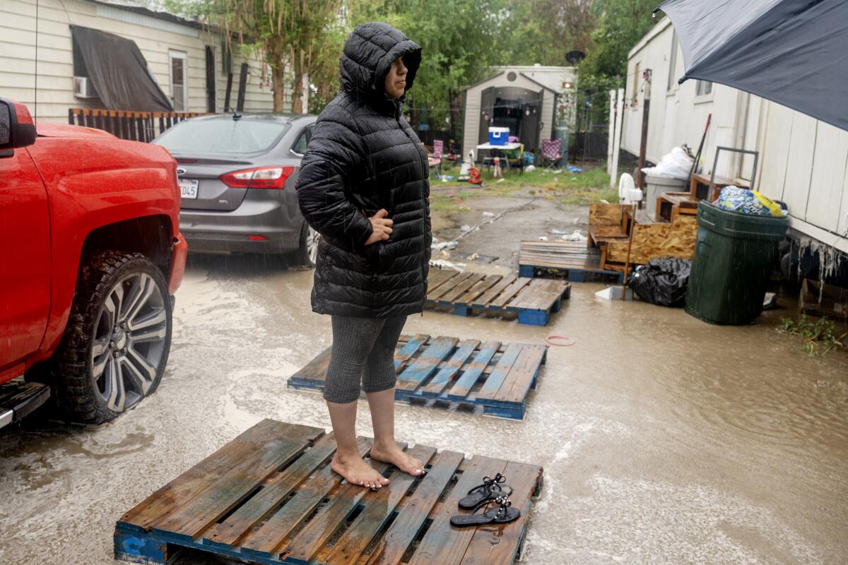 A woman stands on a wooden pallet surrounded by floodwaters