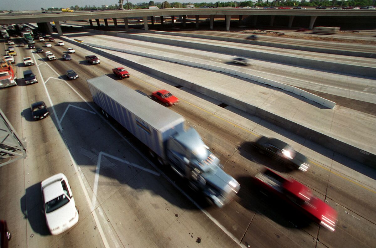 A truck and cars are shown moving along a freeway