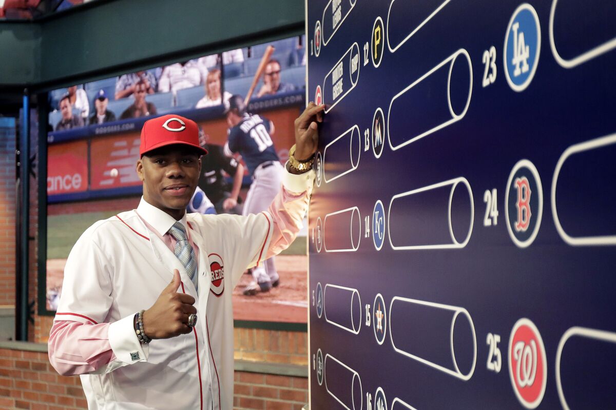 FILE_ Hunter Greene, a pitcher and shortstop from Notre Dame High School in Sherman Oaks, Calif., poses for photographs after putting his name on the board moments after being selected No. 2 by the Cincinnati Reds in the first round of the Major League Baseball draft on June 12, 2017, in Secaucus, N.J. Greene's rise to the Cincinnati Reds' starting rotation appeared possible with the offseason departure of Wade Miley to the Cubs and even more opportunity has arisen with Sonny Gray’s recent trade to the Twins. (AP Photo/Julio Cortez, File)