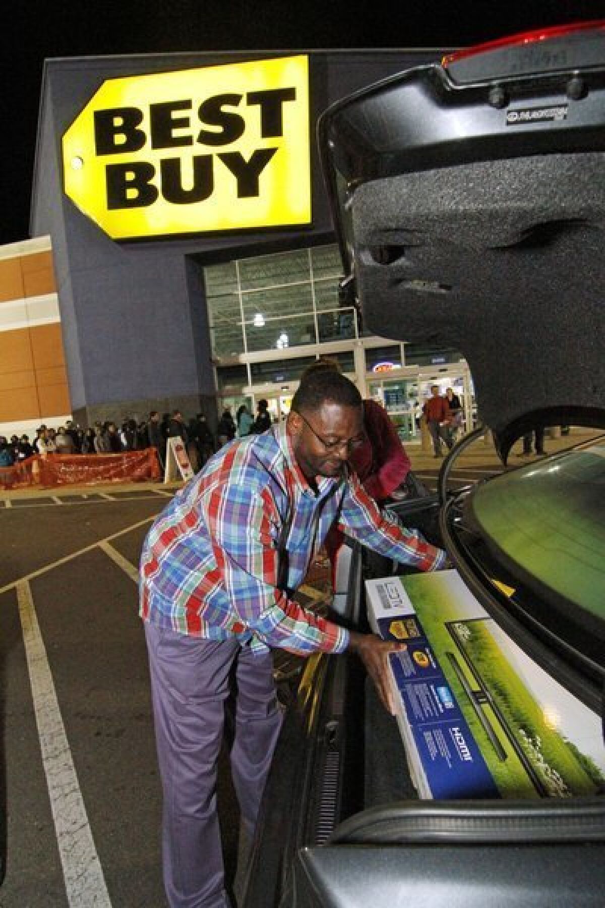 Arthur Vardaman of Madison, Miss., places a new television into the trunk of his car outside a Best Buy store in Jackson, Miss.
