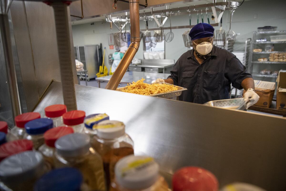 El chef O.J. Hutson cocina papas fritas en una freidora mientras se prepara para el almuerzo en Union Rescue Mission.