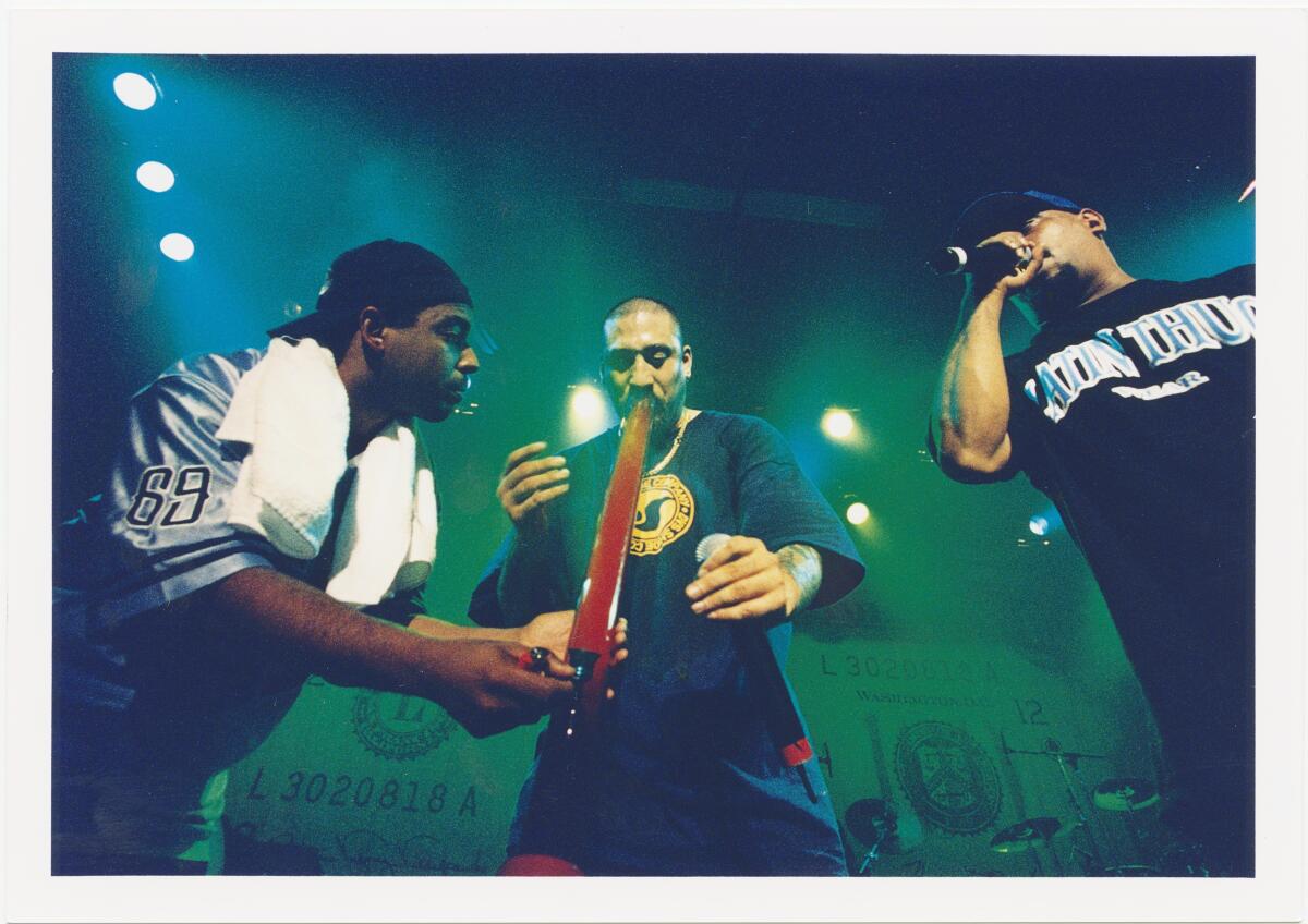 A rap trio onstage, with one member taking a hit from a large bong.