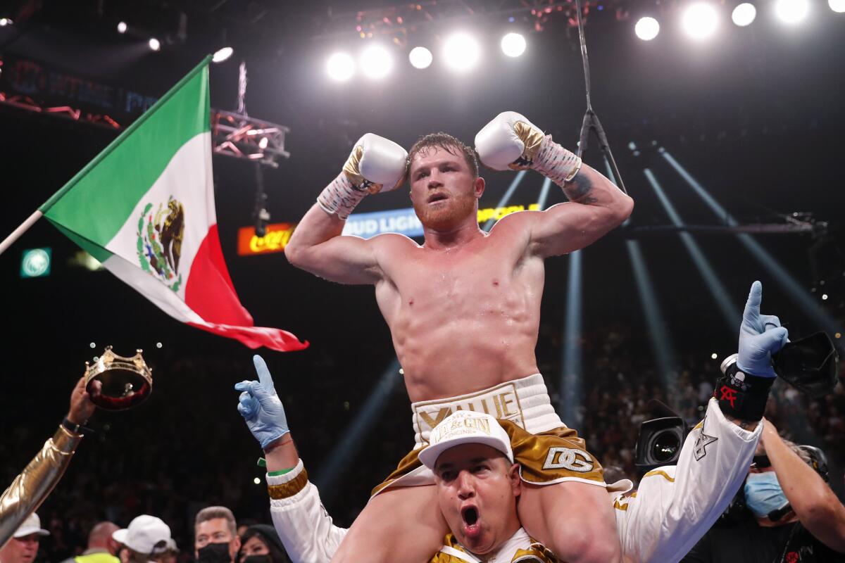 Canelo Álvarez celebrates in the ring on the shoulders of one of this trainers.