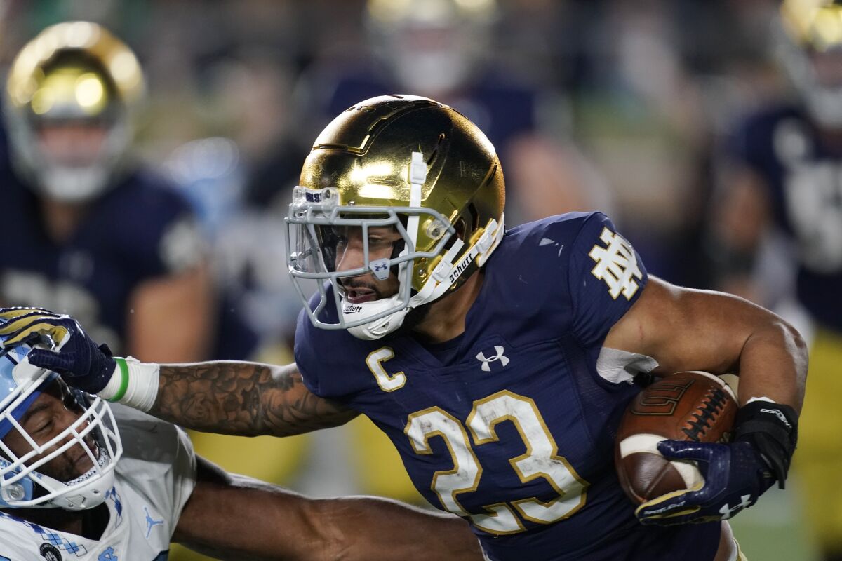 Notre Dame running back Kyren Williams (23) stiff arms a North Carolina defender for a 91-yard touchdown run during the second half of an NCAA college football game, Saturday, Oct. 30, 2021, in South Bend, Ind. (AP Photo/Carlos Osorio)