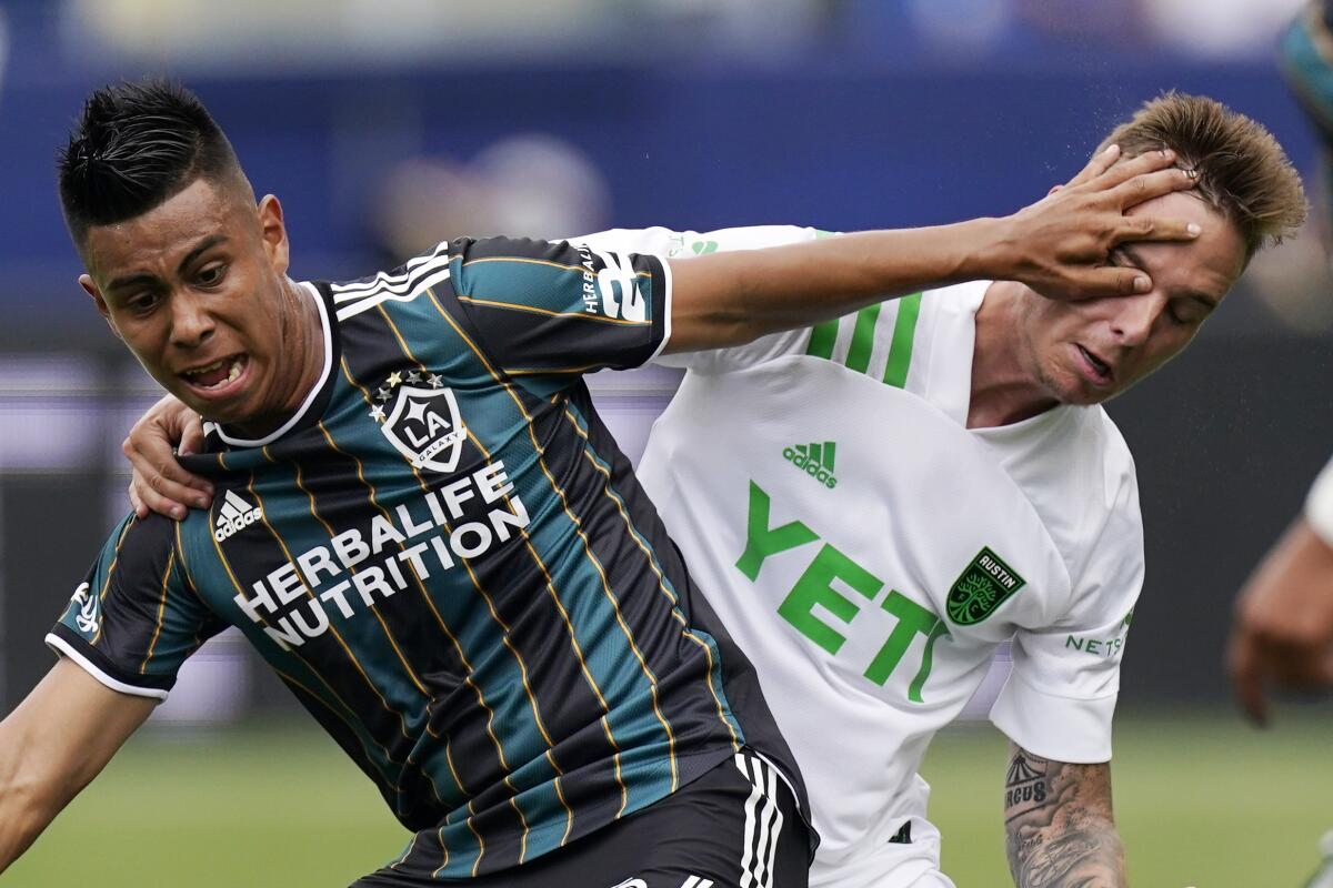 LA Galaxy midfielder Efrain Alvarez, left, hits Austin FC defender Zan Kolmanic in the face 