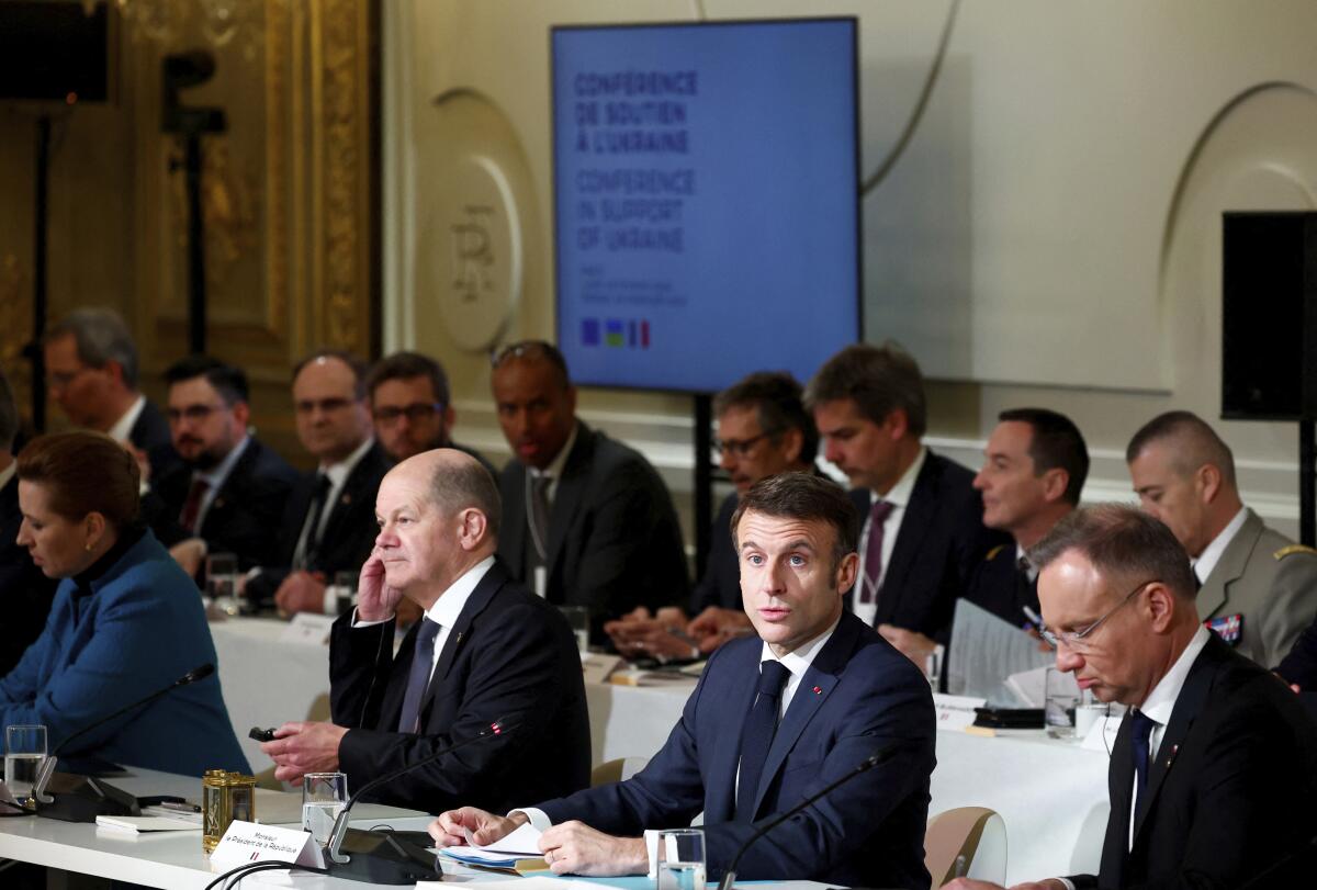 French President Emmanuel Macron addresses an event while seated at a table.