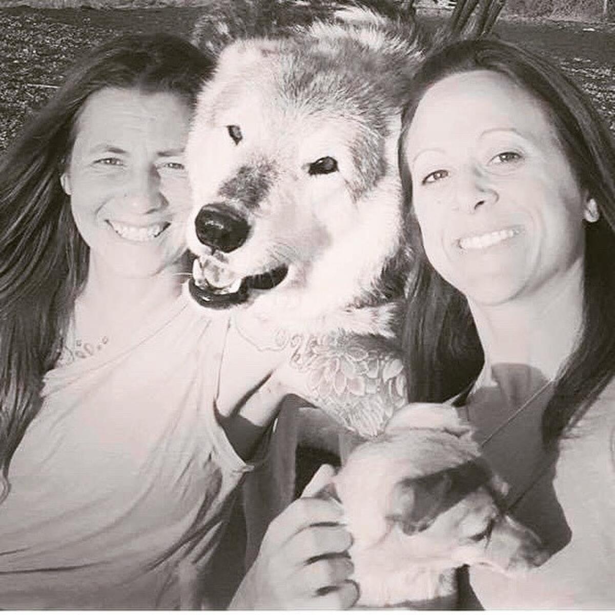 Lauren Freiser, left, and Lori DeProspo, right, with their wolf/malamute hybrid "Wolfie" at the King Wolf Animal Sanctuary in Ramona.