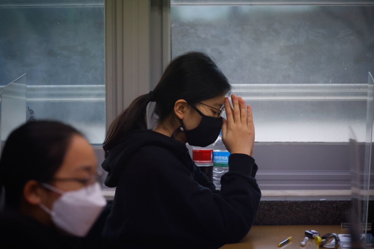 A student wearing a face mask prays before the start of the annual college entrance examination amid the coronavirus pandemic at an exam hall in Seoul, South Korea, Thursday, Dec. 3, 2020. South Korean officials are urging people to remain at home if possible and cancel gatherings as about half a million students prepare for a crucial national college exam. (Kim Hong-Ji/Pool Photo via AP)