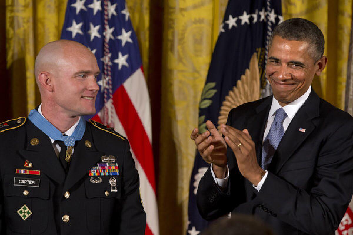 President Obama applauds during a ceremony in the East Room of the White House at which he awarded Army Staff Sgt. Ty M. Carter, left, the Medal of Honor for conspicuous gallantry in the Afghan war.