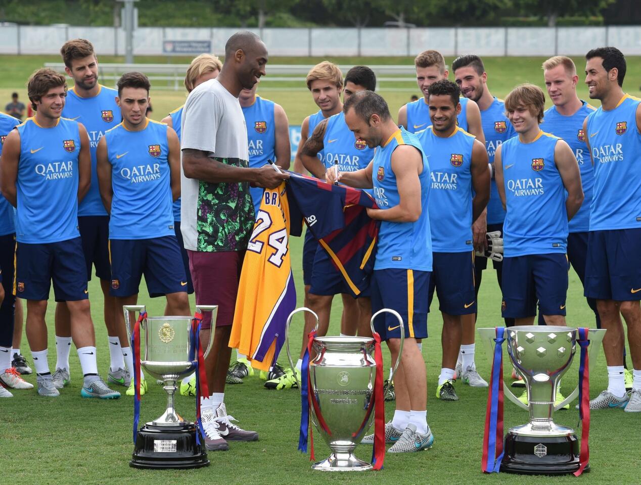 Los Angeles Lakers basketball star Kobe Bryant(C-L) watches as Barcelona team captain Andrés Iniesta Luján (C-R) signs a jersey watched by other members of the Barcelona football team before a training session at the StarHub Stadium in Carson on July 20, 2015. Barcelona will play the LA Galaxy in an International Champions Cup match on July 21. AFP PHOTO/MARK RALSTONMARK RALSTON/AFP/Getty Images ** OUTS - ELSENT, FPG - OUTS * NM, PH, VA if sourced by CT, LA or MoD **