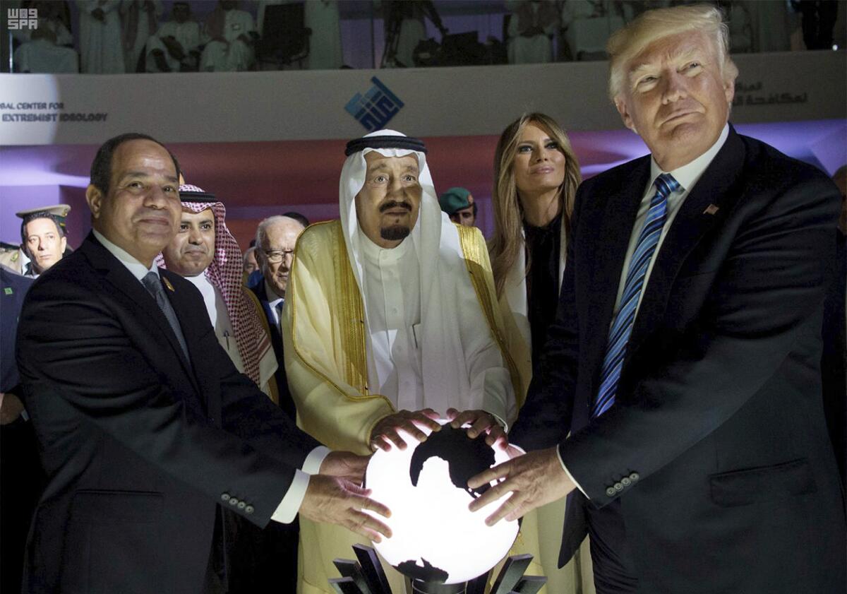 A bearded man in Arabian robe and headdress, center, is flanked by two men in suits and ties, with their hands on an orb
