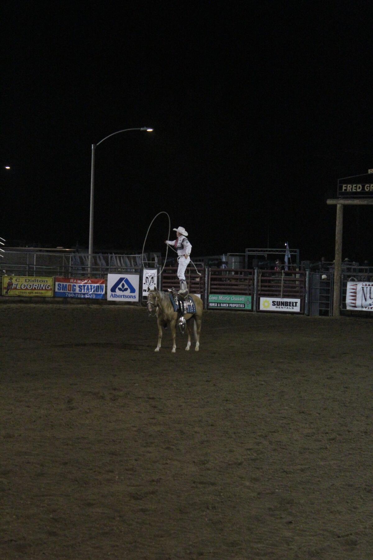 Rider Kiesner preparing to jump through the spinning rope while standing on his horse.
