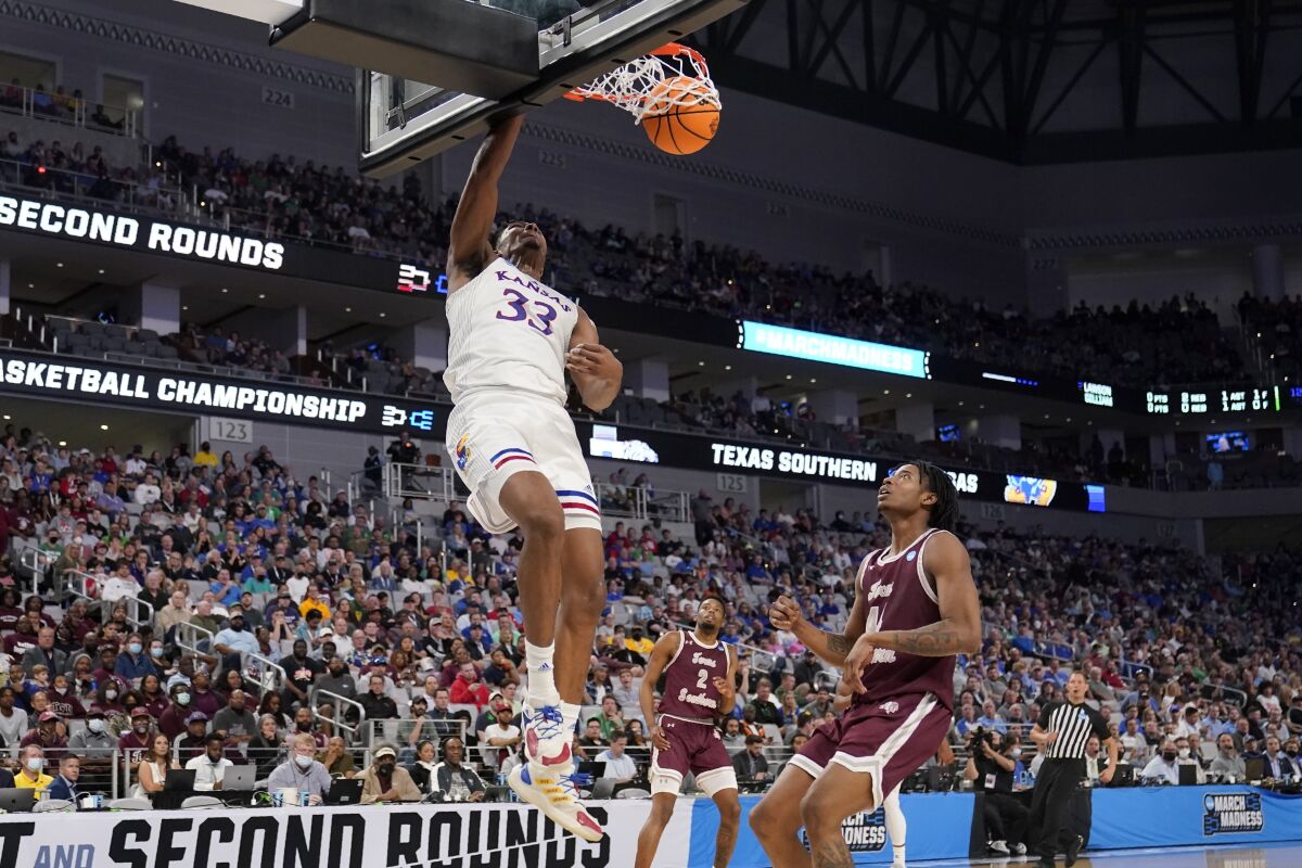 Kansas forward David McCormack (33) dunks as Texas Southern guard AJ Lawson (2) and forward Brison Gresham (44) look on in the first half of a first-round game in the NCAA college basketball tournament in Fort Worth, Texas, Thursday, March 17, 2022. (AP Photo/Tony Gutierrez)