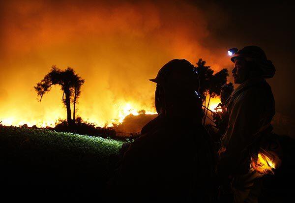 L.A. County firefighters watch the flames in front of a home in Rancho Palos Verdes.