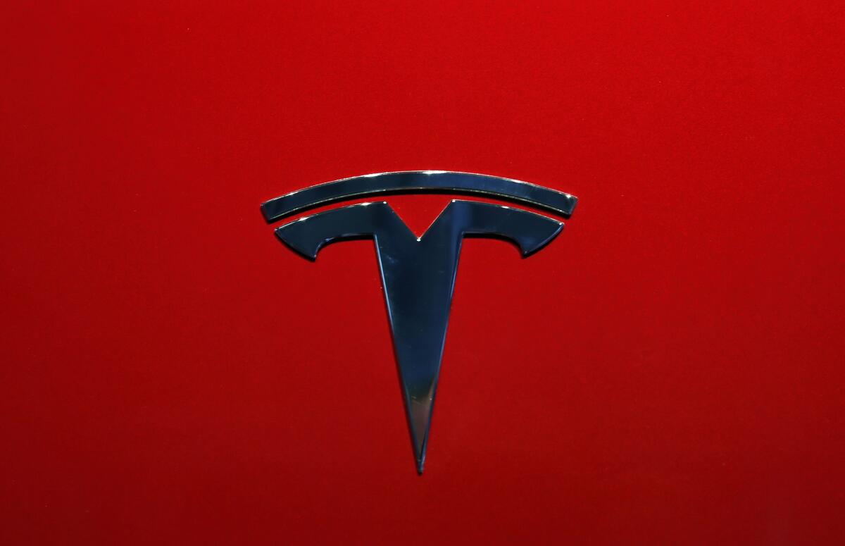 The logo of a Tesla on a red background.