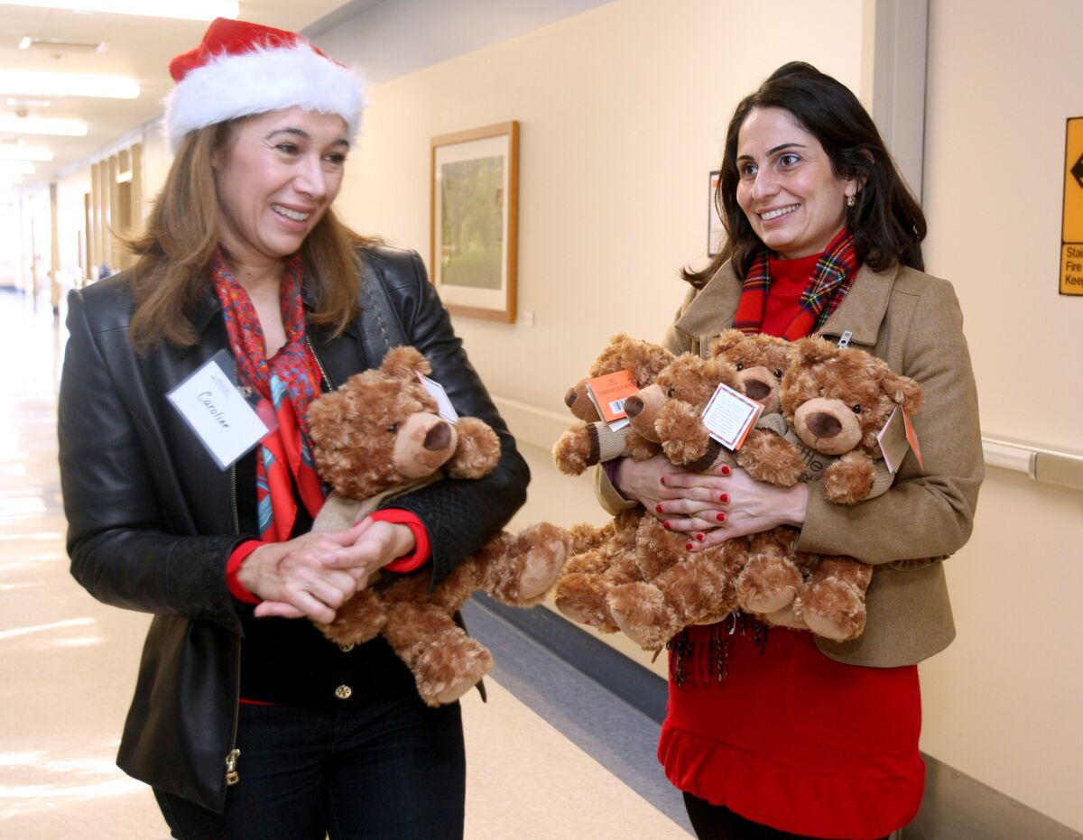 Volunteer Caroline Tufenkian, left, and Glendale Adventist Medical Center marketing director Alina Dersarkissian, right, help pass out teddy bears to patients for the holidays, at GAMC in Glendale on Wednesday, Dec. 23, 2015. Sixty stuffed bears from Bloomingdale's were handed out to patients throughout the hospital.