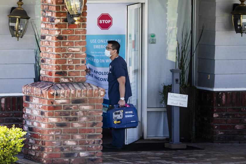 YUCAIPA, CA - APRIL 1, 2020: A medical staff member carries a digital inverter generator into Cedar Mountain Post Acute nursing home after 51 residents and 6 staff members have tested positive for coronavirus on April 1, 2020 in Yucaipa, California. Two residents have died. The city of Yucaipa has the most positive cases of any city in San Bernardino County.(Gina Ferazzi/Los AngelesTimes)