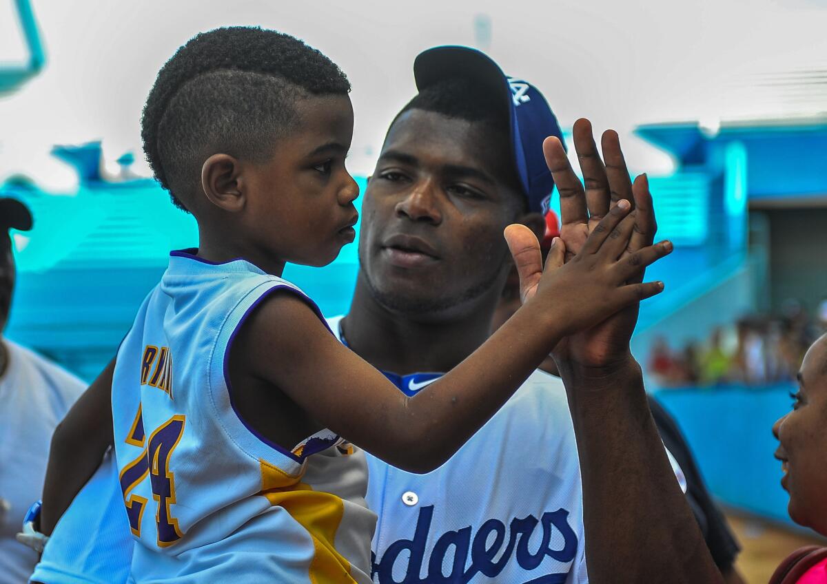 Dodgers outfielder Yasiel Puig holds his nephew during a clinic at Esadio Latinamericano in Havana during a MLB goodwill tour in Cuba.