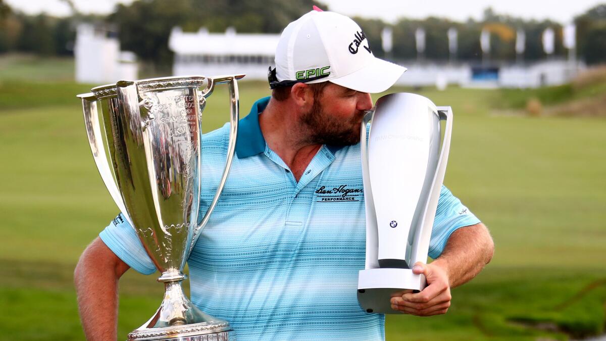 Marc Leishman celebrates with his trophies after winning the BMW Championship at Conway Farms Golf Club on Sunday.