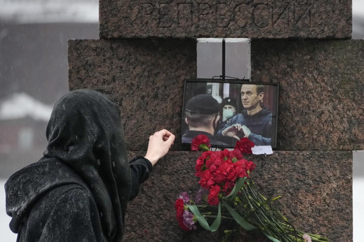 A woman touches a photo of Alexei Navalny after laying flowers at the Memorial to Victims of Political Repression.
