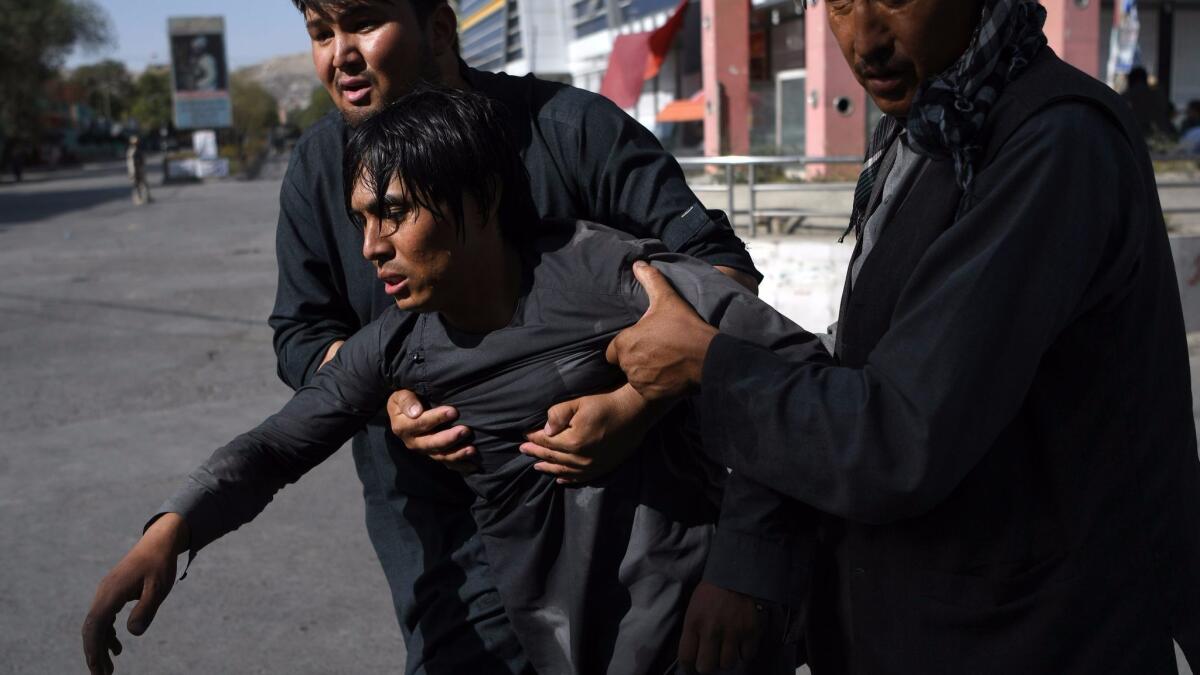 Two men carry a wounded friend from the site of a suicide attack that targeted a Shiite mosque in Kabul, Afghanistan, on Aug. 25