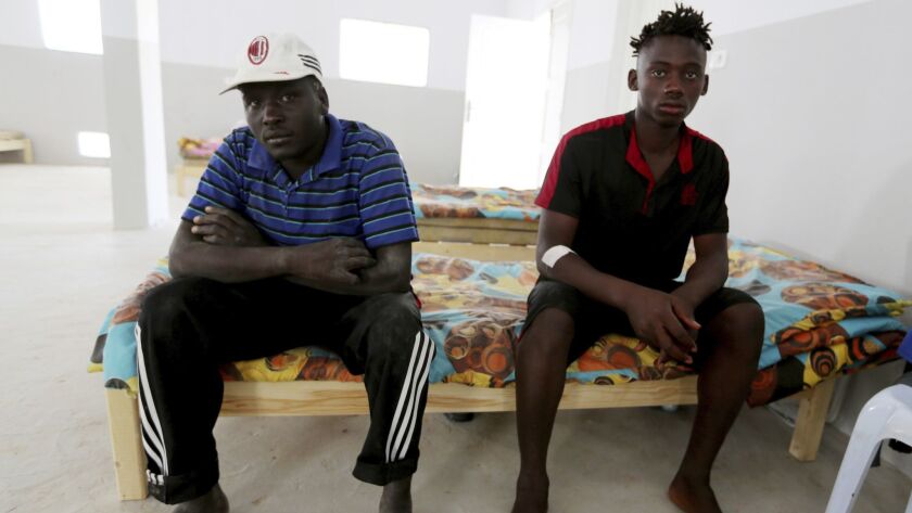 An unidentified Malian survivor, right, of a shipwreck sits in the Red Crescent center of Zarzis, southern Tunisia on July 4. The U.N. migration agency said a boat carrying 86 migrants from Libya sank in the Mediterranean overnight.