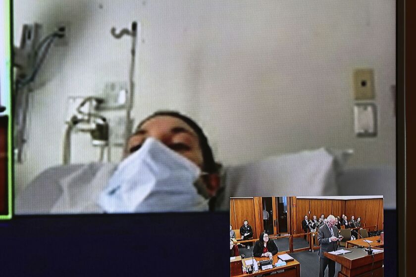 In this video screen image, Lindsay Clancy with a surgical mask over her face in a hospital appears during her arraignment on charges regarding her three children's deaths at Plymouth District Court Tuesday, Feb. 7, 2023, in Plymouth, Mass. With District Court Judge John Canavan as the presiding judge the defendant participated remotely through videoconference. Not guilty pleas were entered on behalf of 32-year-old Clancy to charges including murder, strangulation and assault and battery at her arraignment. (David Ryan/The Boston Globe via AP, Pool)
