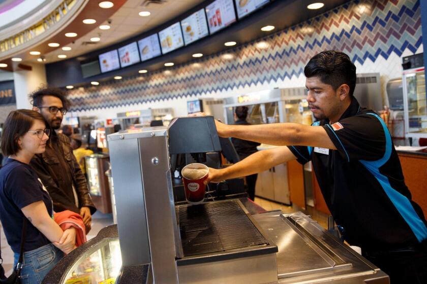 An employee dispenses a soft drink for customers in the concessions area at the Regal Cinemas L.A. LIVE Stadium 14 movie theater on Friday, May 12, 2017 in Los Angeles, Calif. (Patrick T. Fallon/ For The Los Angeles Times)