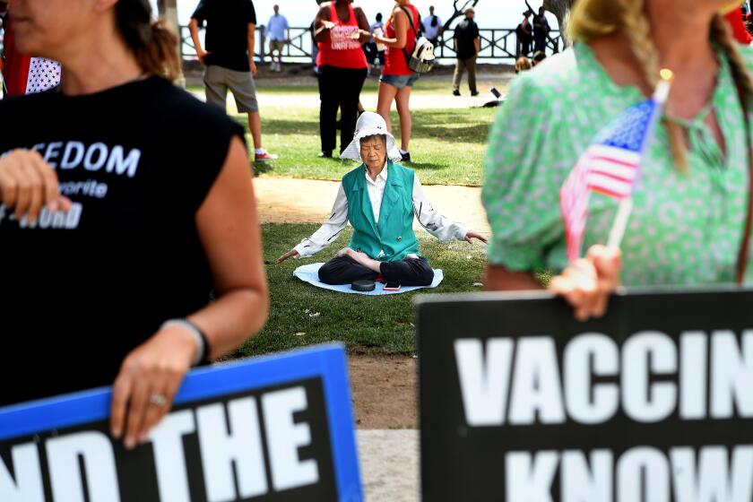 LOS ANGELES, CA. August 29, 2021: A woman meditates next to a rally near the Santa Monica Pier for a "worldwide rally for freedom" Sunday. Hundreds of people attended the event at Tongva Park. (Wally Skalij/Los Angeles Times)