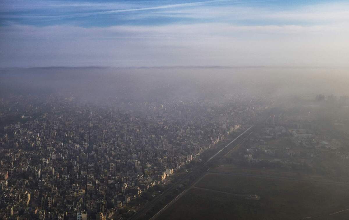 A blanket of smog extends over a densely populated neighborhood adjacent to the main airport in New Delhi on March 15, 2016.