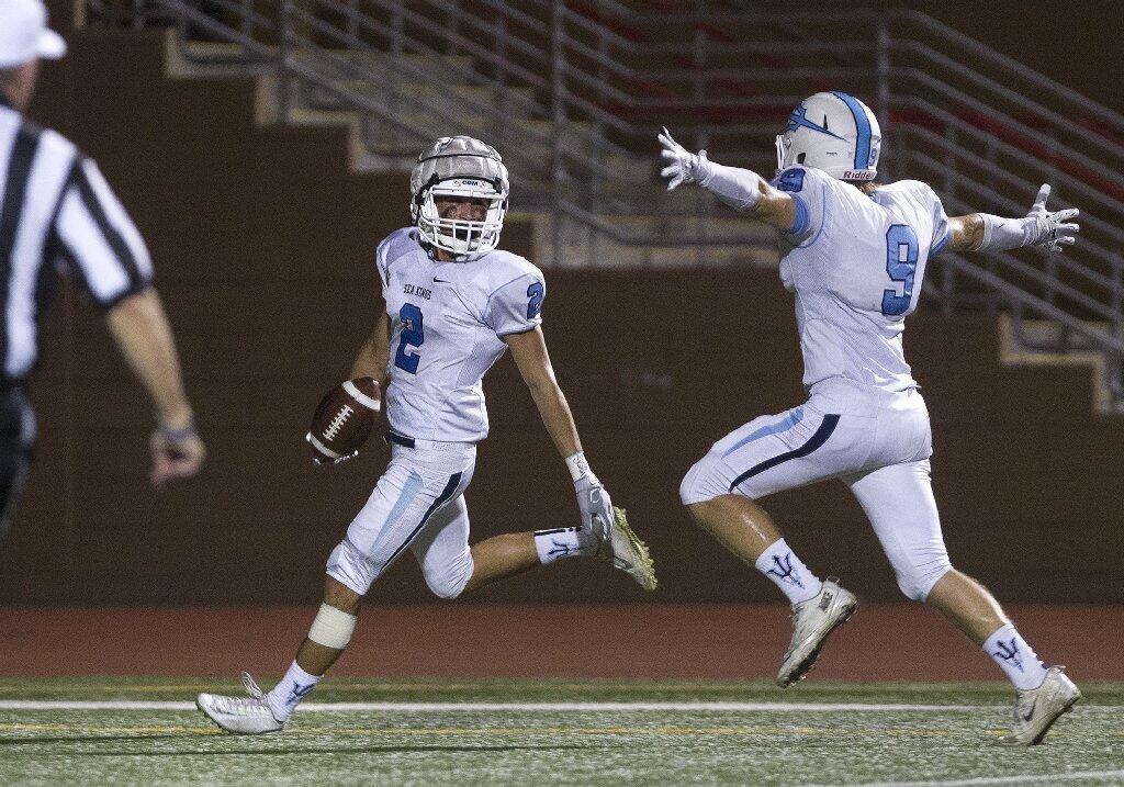 Corona del Mar High's Sutty Barbato (2) looks back at teammate Karl Donovan after scoring a touchdown off a Woodbridge fumble during the first half in a Pacific Coast League opener at University High in Irvine on Friday.