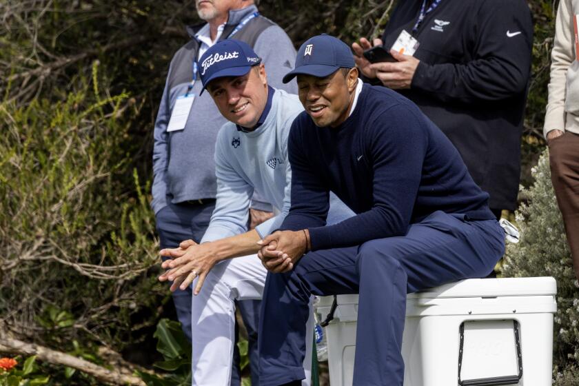 Justin Thomas, left, and Tiger Woods take a break on an ice chest at the 4th tee box
